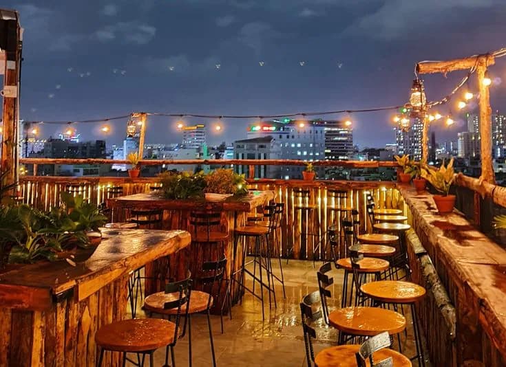 Rooftop bar with string lights and tables overlooking the city at night