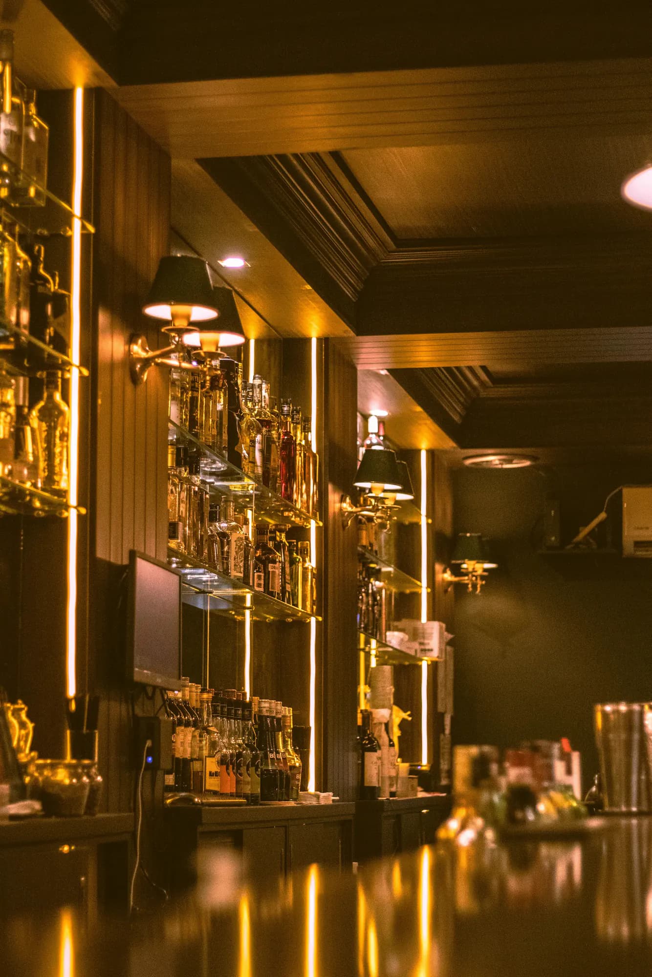 A golden-lit bar counter stretching into a wood-panelled room